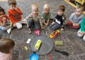 Dzieci wróżą na dywanie za pomocą butelki