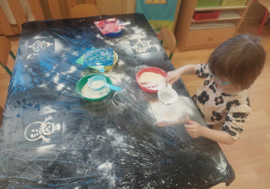 Dziewczynka przesiewa mąkę tworząć swój obrazek
