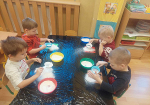 Dzieci bawią się mąką tworząc swoje obrazki