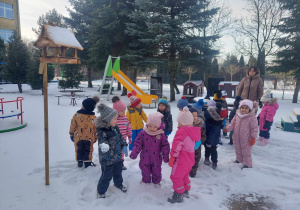 Dzieci stoją przy karmniku
