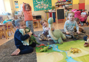 Dzieci bawią się dinozaurami na dywanie