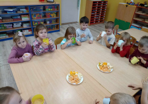 dzieci siedzą przy wspólnym stole i degustują wyciśnięty przez siebie sok