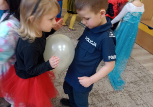 chłopiec tańczy z dziewczynką z balonem między brzuchami