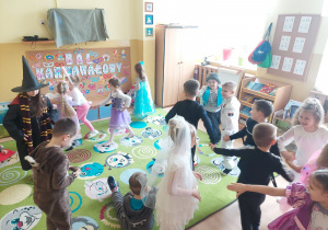 Dzieci trzymają się za ręce i tańczą w rytm muzyki.