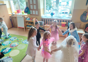 Dziewczynki trzymają się za ręce i tańczą w rytm muzyki.