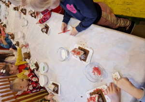 Dzieci ozdabiają swoje piernikowe domki lukrem i kolorową posypką