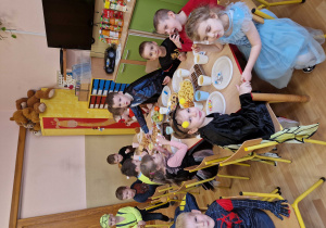 Dzieci siedzą przy stolikach i wspólnie uczestniczą w poczęstunku