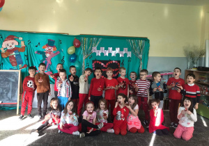 Grupa dzieci ubrana na czerwono pozuje do zdjęcia z Walentynkowymi babeczkami.