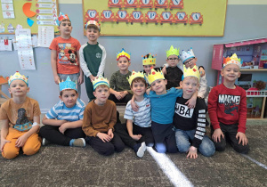 Grupa chłopców na tle napisu "Dzień Chłopaka" pozuje w koronach do zdjęcia.