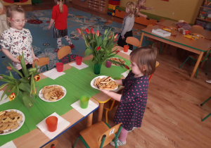 Dziewczynki dekorują stół i rozstawiają ciasteczka