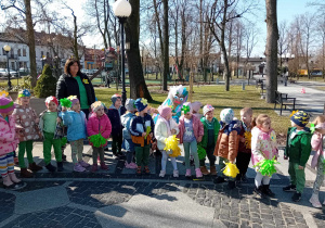 Dzieci stoja w szeregu, w rękach trzymają żółte i zielone pompony.