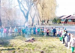 Dzieci stoją w okręgu, na środku pali się kukła ze słomy.