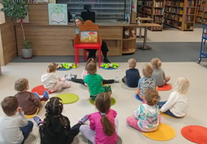 dzieci słuchają bajki czytanej przez panią z biblioteki