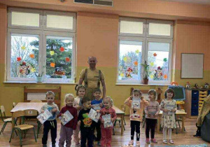 Dzieci stoją w grupie wraz z strażakiem, trzymają w rękach dyplomy