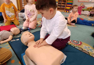 Dziecko ćwiczy na fantomie uciśnięcia klatki piersiowej