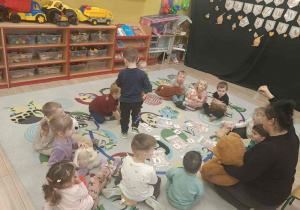 Dzieci siedzą w kole i przedstawiają swoje pluszowe misie.