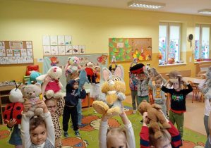 Dzieci bawią się na dywanie ze swoimi pluszowymi misiami.