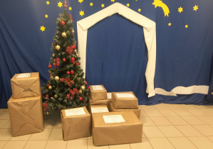 Zdjęcie przedstawia zapakowane paczki , choinkę oraz szopkę bożonarodzeniową