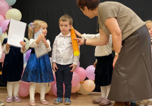 Pani Dyrektor pasuje na przedszkolaka za pomocą dotknięcia symbolicznym ołówkiem w ramię