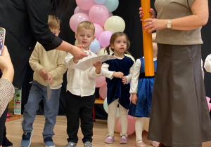 Pani Dyrektor pasuje na przedszkolaka za pomocą dotknięcia symbolicznym ołówkiem w ramię