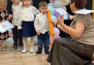 Pani Dyrektor pasuje na przedszkolaka za pomocą dotknięcia symbolicznym ołówkiem w ramię