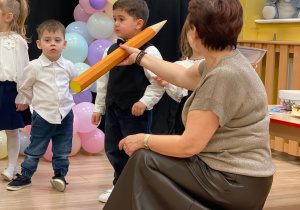 Pani Dyrektor pasuje na przedszkolaka za pomocą dotknięcia symbolicznym ołówkiem w ramię