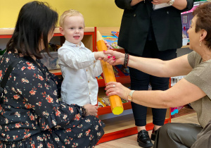 Pani Dyrektor pasuje na przedszkolaka za pomocą dotknięcia symbolicznym ołówkiem w ramię