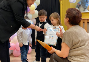 Pani Dyrektor pasuje na przedszkolaka za pomocą dotknięcia symbolicznym ołówkiem w ramię