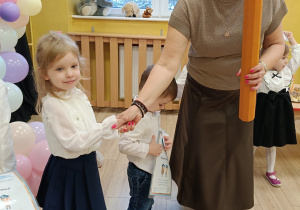 Pani dyrektor ściska dłoń dziewczynki gratulując jej