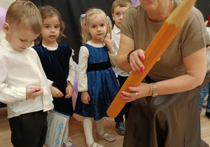 Pani dyrektor kuca przed dziećmi gratulując im występu