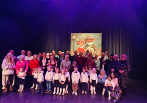 Dzieci wraz z Dziadkami pozują do zdjęcia na drewnianej scenie