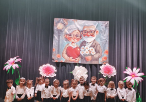 Dzieci pozują do zdjęcia stojąc na drewnianej scenie