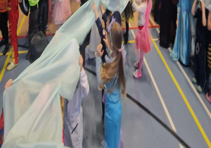 Dzieci trzymają w dłoniach błękitną tkaniną symbolizującą magiczne dywany