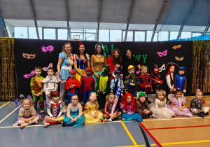 Dzieci pozują do zdjęcia na tle napisu Bal Karnawałowy