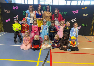 Dzieci pozują do zdjęcia na tle napisu Bal Karnawałowy