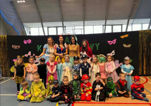 Dzieci pozują do zdjęcia na tle napisu Bal Karnawałowy