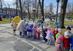 Dzieci świętują nadejście wiosny, trzymają w ręce balony, są ubrane w kolorowe stroje