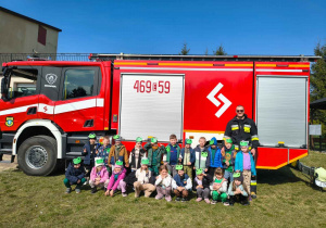 Dzieci pozują do zdjęcia przy wozie strażackim