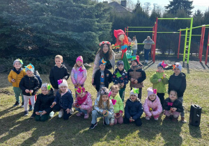 Dzieci pozują do zdjęcia, nauczycielka trzyma w ręku marzannę