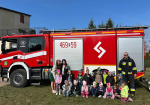 Dzieci pozują do zdjęcia na tle wozu strażackiego