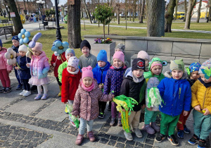 Dzieci podczas marszu, trzymają w ręce zielone pomponcy