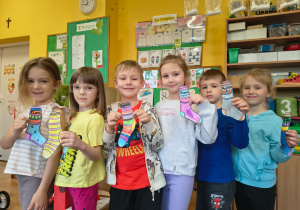 Dzieci stoją w grupie trzymając w ręce pokolorowane papierowe skarpetki