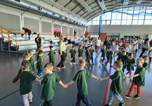 Dzieci stoją w kole trzymając się ręce.