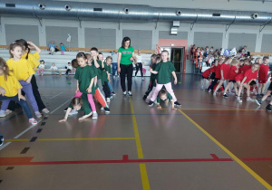 Dzieci stoją rozkrakiem, inne dzieci przechodzą pod nimi.