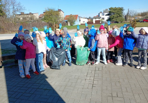 Dzieci w jednorazowych rękawiczkach pokazują ile worków śmieci udało im się zebrać podczas akcji ekologicznej
