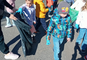 Dzieci na spacerze zbierają śmieci