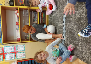 dzieci układają tory kolejowe na dywanie