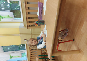 dziewczynka maluje kolorowanki przy stoliku