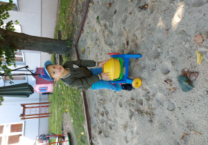 chłopiec bawi się plastikową koparką w piaskownicy