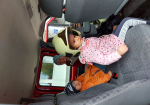 Troje dzieci siedzi w wozie strażackim
